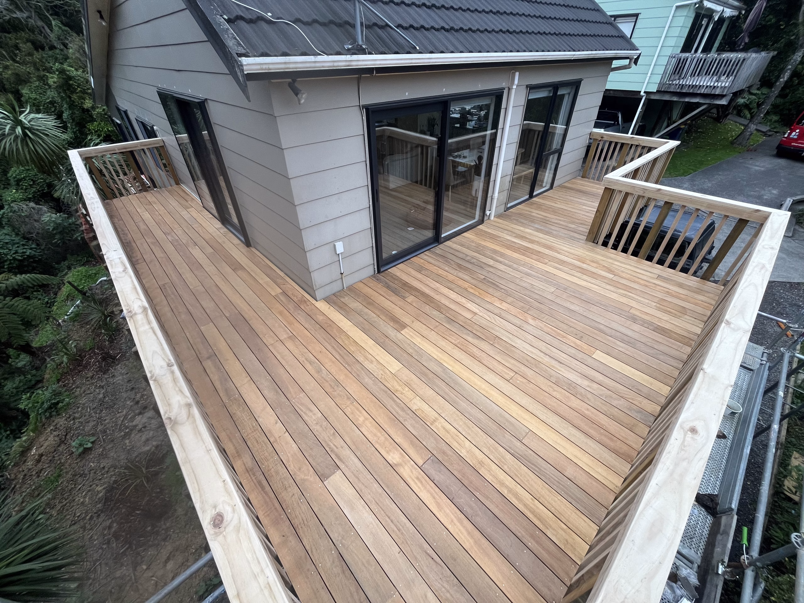 Newly built large timber deck with wooden balustrades attached to a house with sliding glass doors